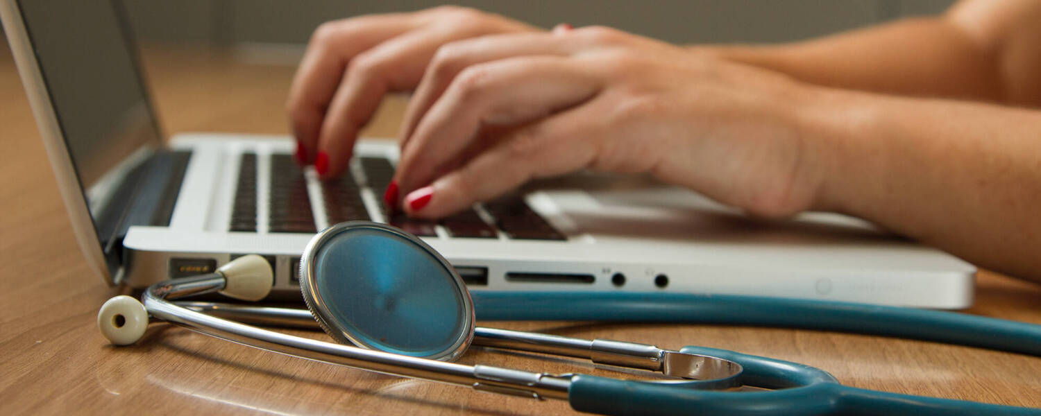 Person typing with stethoscope