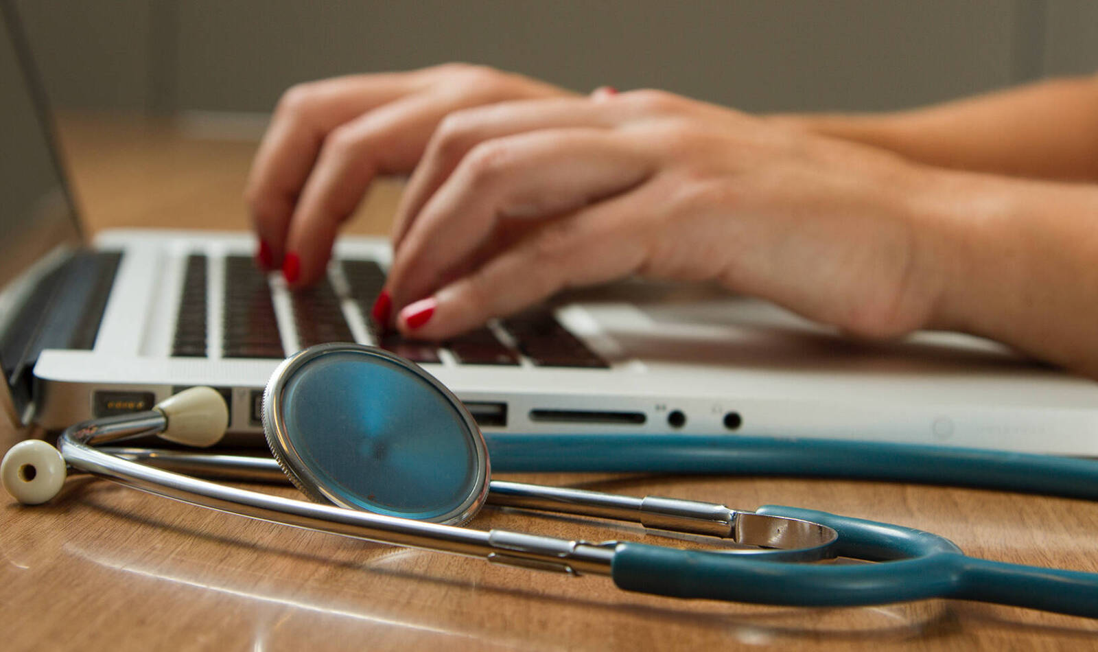 Person typing with stethoscope