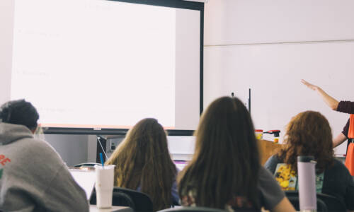 Salem College students in class with the professor pointing to a screen
