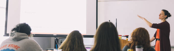 Salem College students in class with the professor pointing to a screen