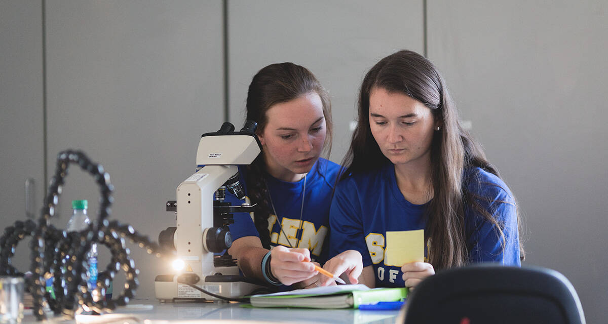 Salem College students studying with a microscope