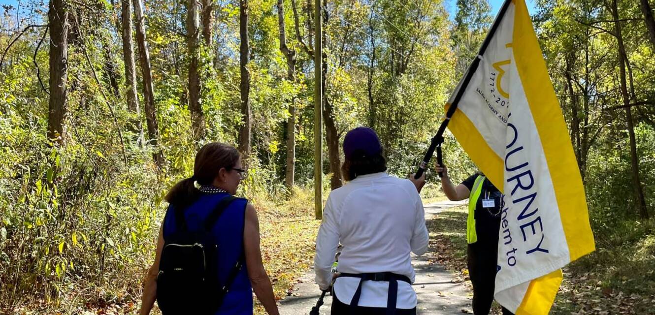 Salem College community members walking with the Journey to Salem flag