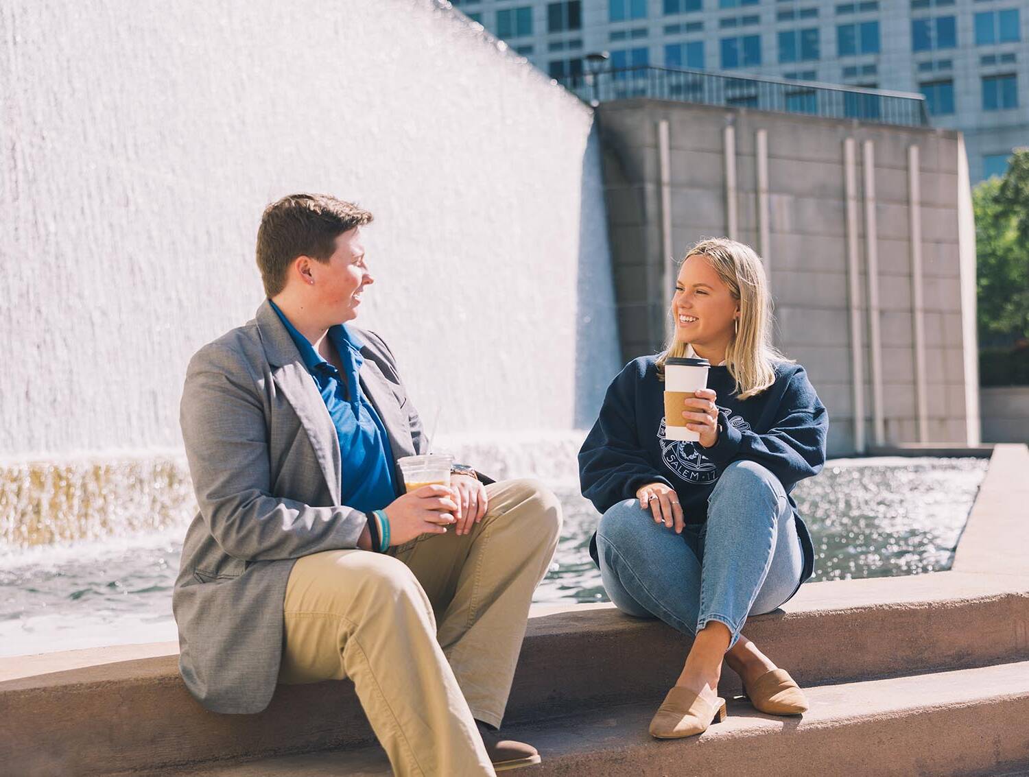 Two people enjoying a coffee sitting on stairs and chatting