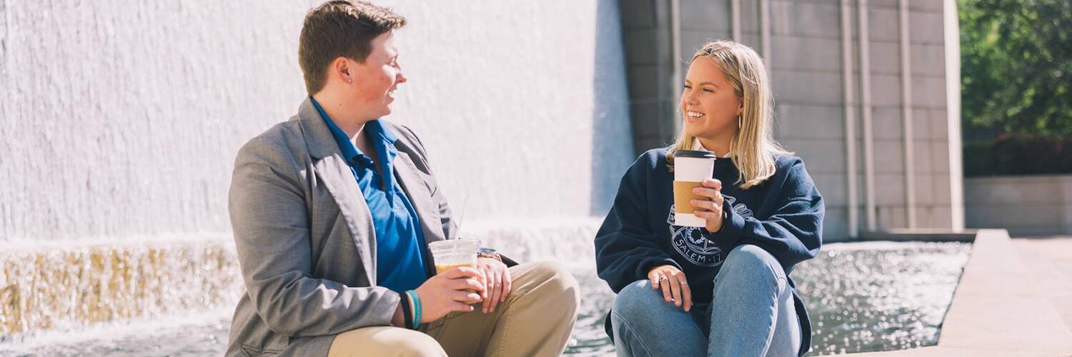 Two people enjoying a coffee sitting on stairs and chatting