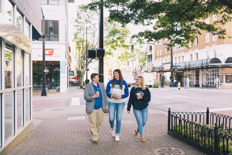 Three students on a walk together drinking coffee