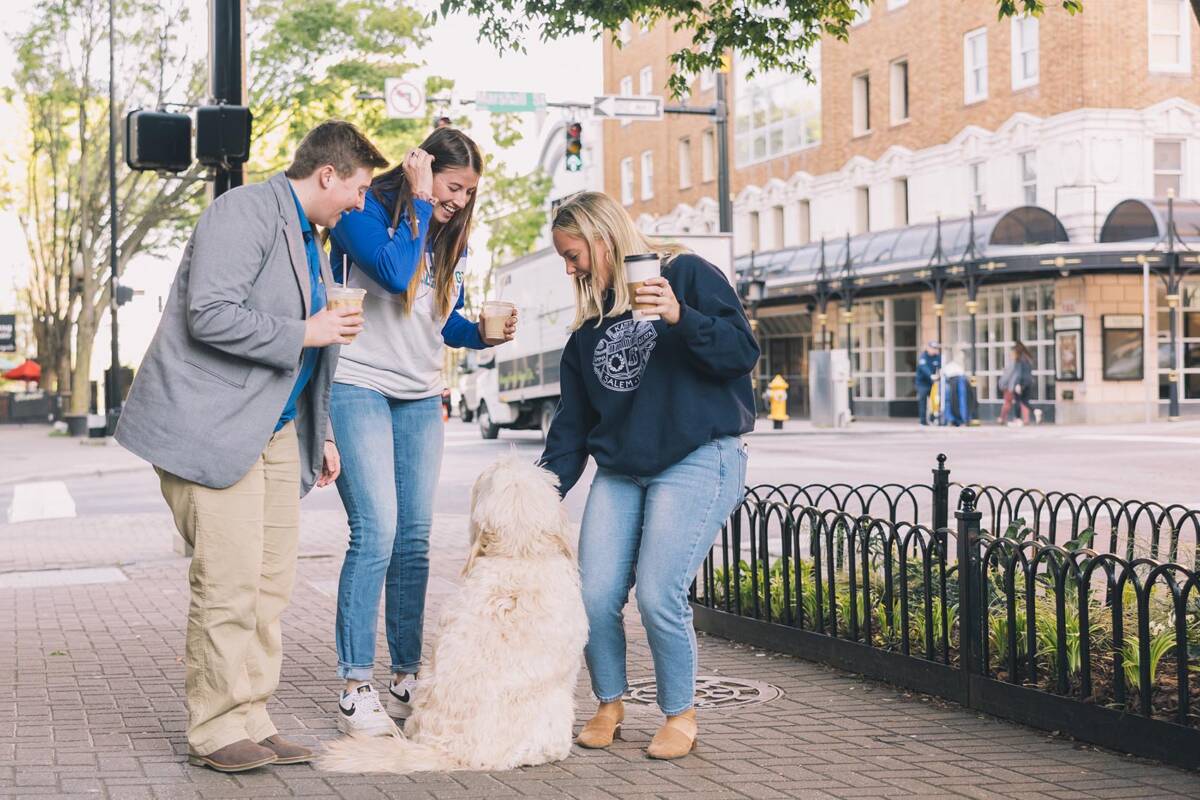 Students on walk outside petting a dog
